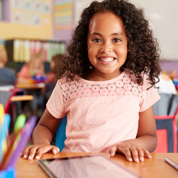 little girl in pink shirt smiling in classroom