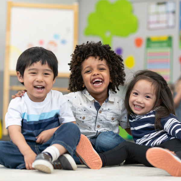 Three little kids sitting down smiling