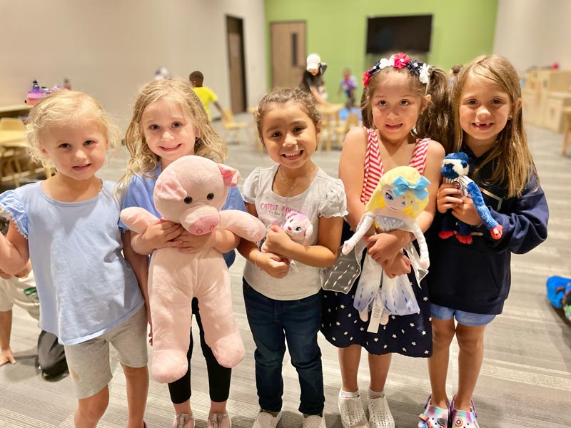 Five preschool girls holding plush toys at Lionheart Children's Academy