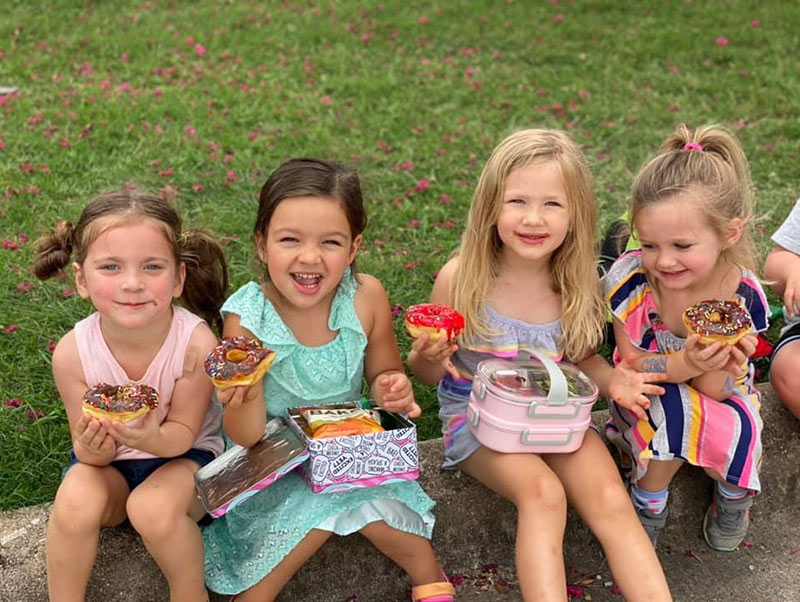 Four preschool girls enjoying donuts at Lionheart Children's Academy