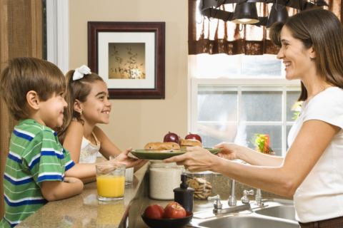 Mother serving breakfast to her young son and daughter