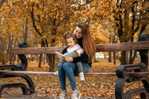 The Mother and daughter enjoying story time on a park bench.