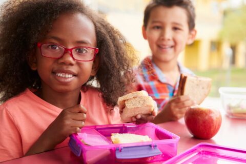 Two young children enjoying sandwiches