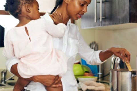 Mother holding daughter while cooking