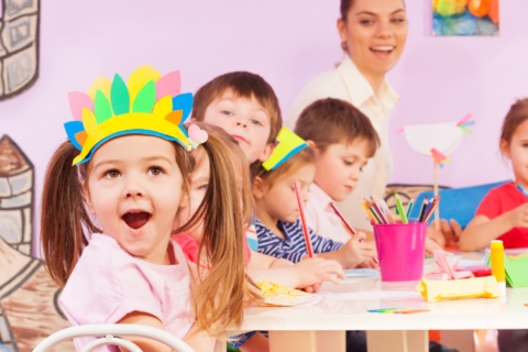 The Joyful young girl in a vibrant crown engaging in arts and crafts alongside her classmates.