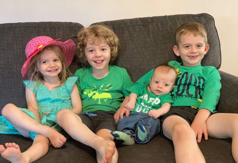 Newborn and children sitting on couch wearing green for St. Patricks Day 