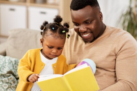 A father reads with his toddler daughter