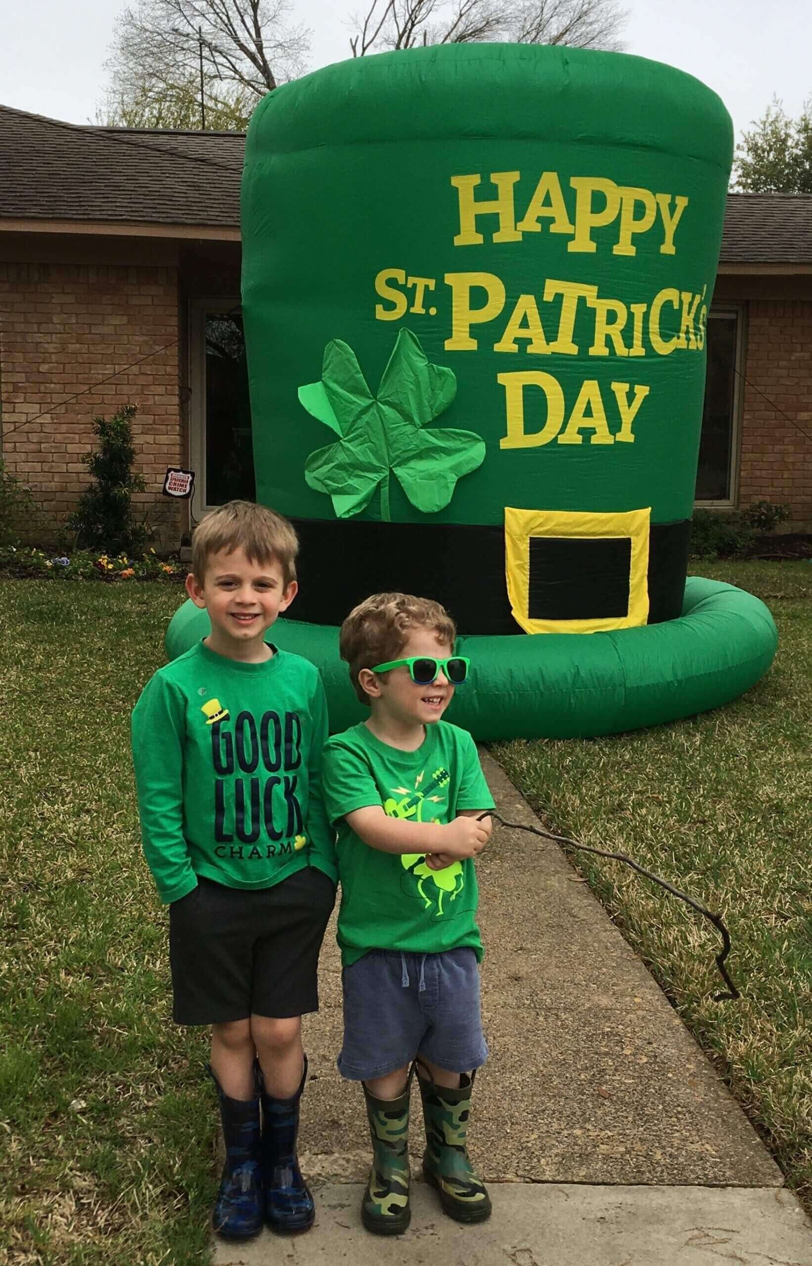 Two boys by giant leprechaun hat during neighborhood scavenger hunt. 